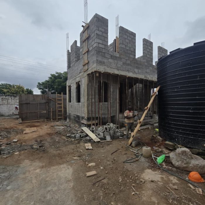 Construction workers laying concrete blocks for a modern building project in the Abelemkpe neighborhood.