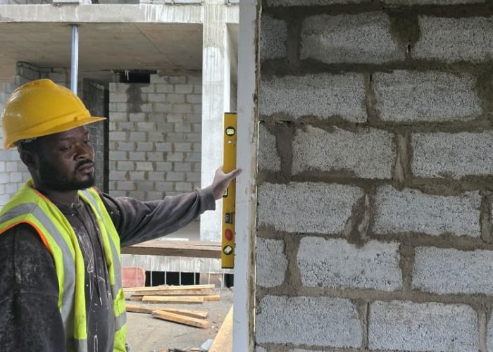 A skilled mason leveling concrete blocks during structural development work in Accra