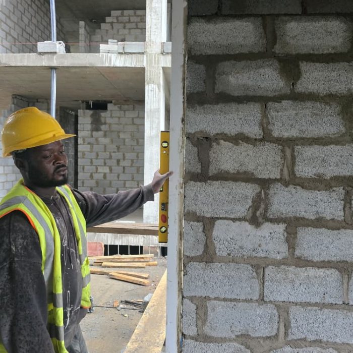 A skilled mason leveling concrete blocks during structural development work in Accra