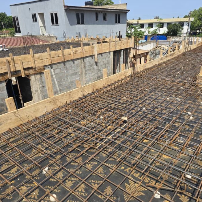Piles of durable concrete hollow blocks and construction materials ready for masonry work at an Abelemkpe site.